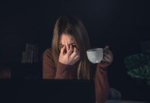 Café após noites mal dormidas pode aumentar risco de enxaqueca mulher com enxaqueca segurando xícara de café