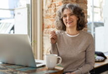 quando os hormônios mudam e a vida também Mulher de 50 anos sorrindo em ambiente de trabalho.