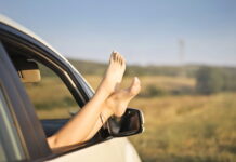viagens longas aumentam o risco de trombose? pessoa com o pés pra cima no carro