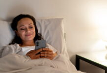 Sono ruim e excesso de telas podem afetar a saúde da pele Celular na cama durante a noite.