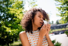 pólen pode intensificar sintomas respiratórios Pessoa espirrando ao ar livre durante a primavera