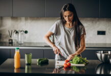 Reeducação alimentar ajuda a manter hábitos no emagrecimento mulher preparando uma refeição saudável na cozinha